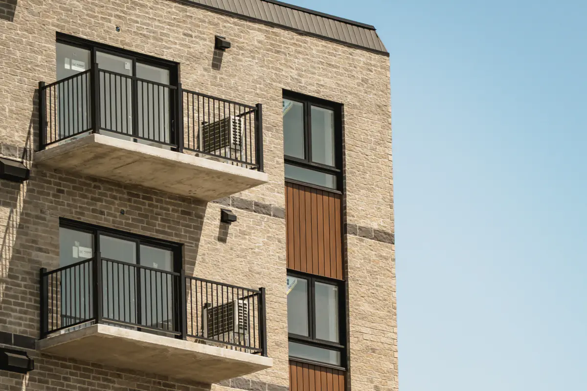 Façade de brique, balcons superposés à barreaux noirs